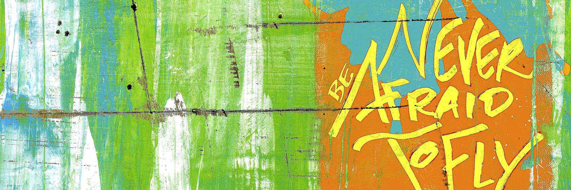 Graffiti in Grün, Gelb, Orange, Hellblau: "Never be afraid to fly"