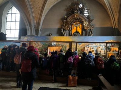 Schüler besuchen eine Adventsszene in einer Kirche